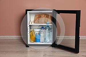 Mini bar filled with food and drinks near pale pink wall indoors