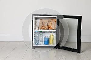 Mini bar filled with food and drinks near white wall indoors