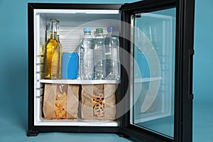 Mini bar filled with food and drinks on turquoise background, closeup