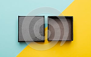 Mini black box product packaging isolated on yellow half blue background. Flat lay Top view.