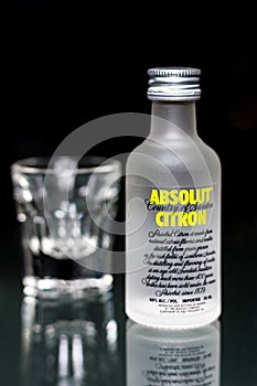 A mini bottle of Absolut citron vodka with a glass