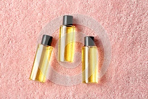 Mini bottles with cosmetic products on towel, flat lay.