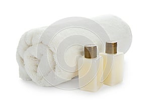 Mini bottles with cosmetic products and towel on white background