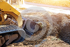 Mini bulldozer working with earth soil while doing landscaping works on construction