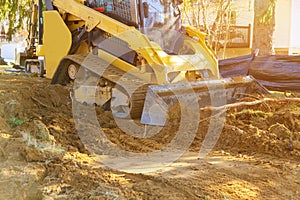 Mini bulldozer working with earth soil while doing landscaping works on construction