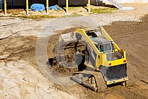 Mini bulldozer working with earth soil while doing landscaping works on construction