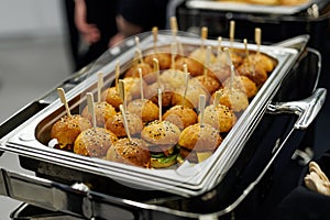 Mini burgers with sesame seeds on a metal tray