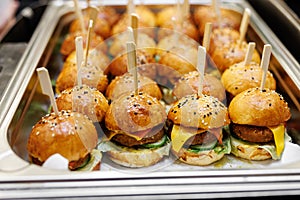 Mini burgers with sesame seeds on a metal tray