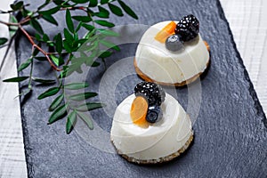 Mini cakes with dried apricots and blackberries on stone slate background close up