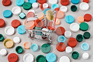 Mini cart with colored plastic caps ready to be recycled. Concept of ecology and plastic recycling