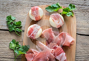 Mini cheese and prosciutto wraps on the wooden board
