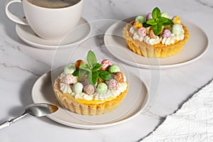 Mini cheesecakes with candy eggs and whipped cream. Pastel colored Easter dessert
