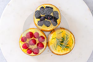 Mini cheesecakes close-up, flat lay. Cheesecake topping ideas. Fresh berries topping, and rosemary and lemon topping