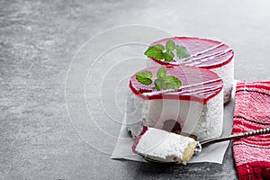 Mini cheesecakes with red fruits jam topping on gray background