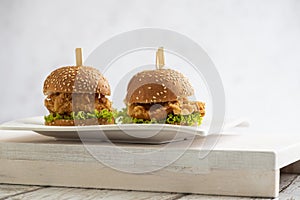 Mini Chicken burgers with lettuce and sticks on a wooden background