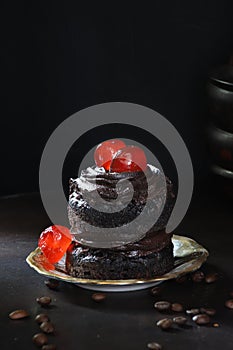 Mini chocolate cake with glace cherries and coffee beans in the foreground