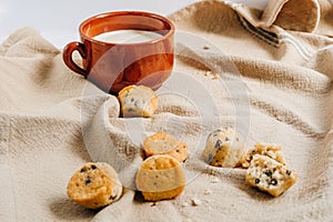 Mini chocolate chip muffins with a mug with milk inside on the background. Breakfast concept