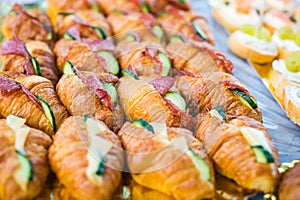 Mini croissants appetizers with cheese and salami in plate on banquet table. Catering snacks for birthday party.