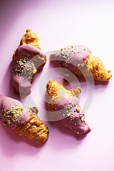 Mini-croissants with ruby chocolate and pistachios on a pink background. Top view