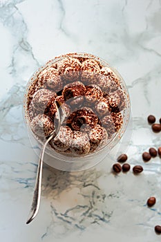 Mini desserts snacks in plastic cups on the table. Tiramisu, traditional Italian dessert on a white marble background..Healthy