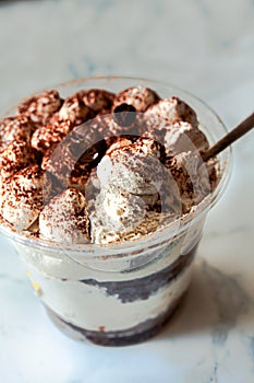 Mini desserts snacks in plastic cups on the table. Tiramisu, traditional Italian dessert on a white marble background..Healthy