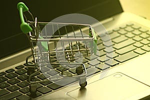 A mini dummy shopping trolley on a lapptop keyboard as a concept for online shopping, saving, business and making money