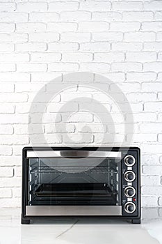 Mini electric oven against white brick wall in the kitchen