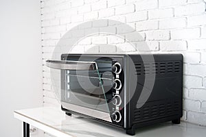 Mini electric oven against white brick wall in the kitchen