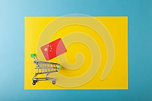 Mini empty supermarket shopping grocery cart, Canada flag on yellow background in blue frame