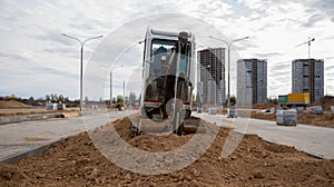 Mini excavator digg trench to lay cables concrete curbs and paving slabs at construction site. Backhoe on earthwork/roadworks