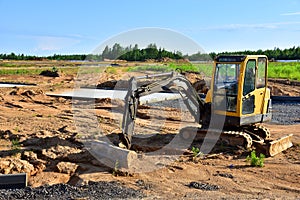 Mini excavator digg trench to lay cables concrete curbs and paving slabs at construction site. Backhoe on earthwork/roadworks