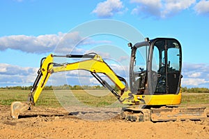 Mini excavator digging earth in a field or forest. Laying underground sewer pipes during the construction of a house. Digging