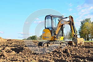 Mini excavator JCB 8025 ZTS digging earth in a field or forest