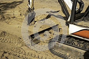 Mini excavator parked on brown dirt with bucket, blade and track