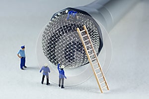 Mini firemen climbing a microphone