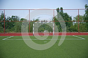 Mini Football Goal On An Artificial Grass . football goal on a green lawn . Football field near fence at day sunny day