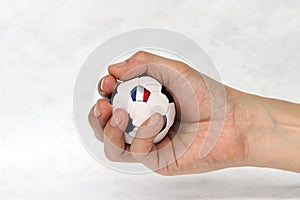 Mini football in hand and one black point of football is France flag on white background