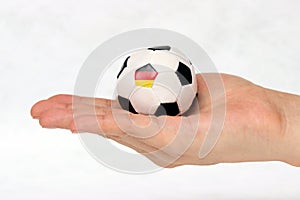 Mini football in hand and one black point of football is Germany flag on white background