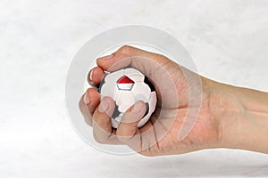 Mini football in hand and one black point of football is Indonesia flag on white background