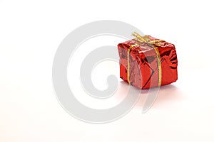 Mini gift box in red reflect gift wrap with golden rope knot isolated on white background.