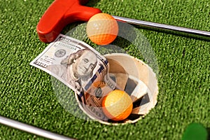 Mini Golf club, ball and money on the artificial grass