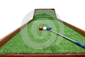 Mini-golf clubs and balls of different colors laid on artificial grass