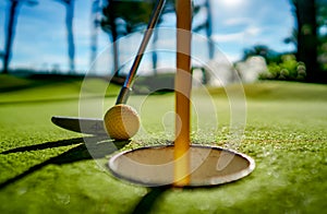 Mini Golf yellow ball with a bat near the hole at sunset