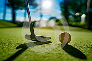 Mini Golf yellow ball with a bat near the hole at sunset