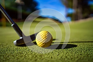 Mini Golf yellow ball with a bat at sunset