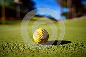 Mini Golf yellow ball on green grass at sunset