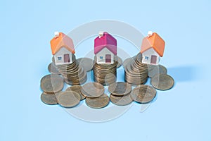 Mini house on stack of coins on a blue background. Concept of Investment property, Real estate, Saving money