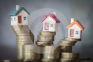 Mini house on stack of coins, Concept of Investment property, Investment risk and uncertainty in the real estate housing market