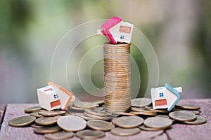 Mini house on stack of coins, Concept of Investment property, Investment risk and uncertainty in the real estate housing market