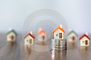 Mini house on stack of coins, Concept of Investment property, Investment risk and uncertainty in the real estate housing market